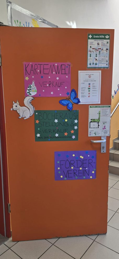 Bunte Plakate mit Tieren und Sternen auf einer orangefarbenen Tür.