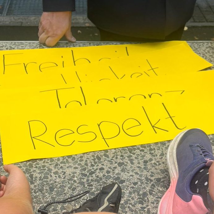 Leere Klassenzimmer mit Tischen, Stühlen und einer Pinnwand im Hintergrund.