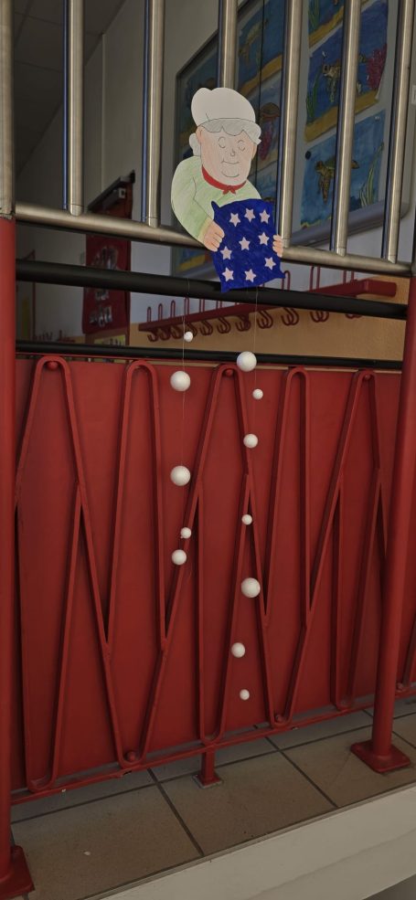 Frau Holle sitzt an einem Geländer mit herunterhängenden Perlen.