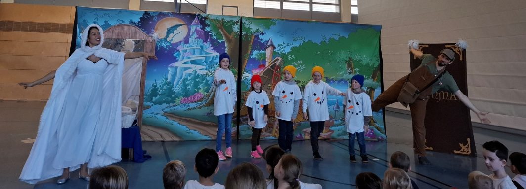 Kinder führen ein Theaterstück auf, verkleidet und vor einer bunten Kulisse.