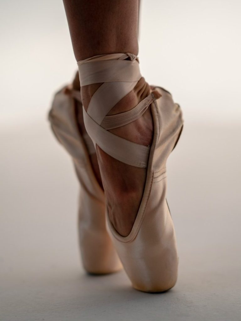 Ballettschuh an einem Fuß, elegant auf den Zehenspitzen balancierend.