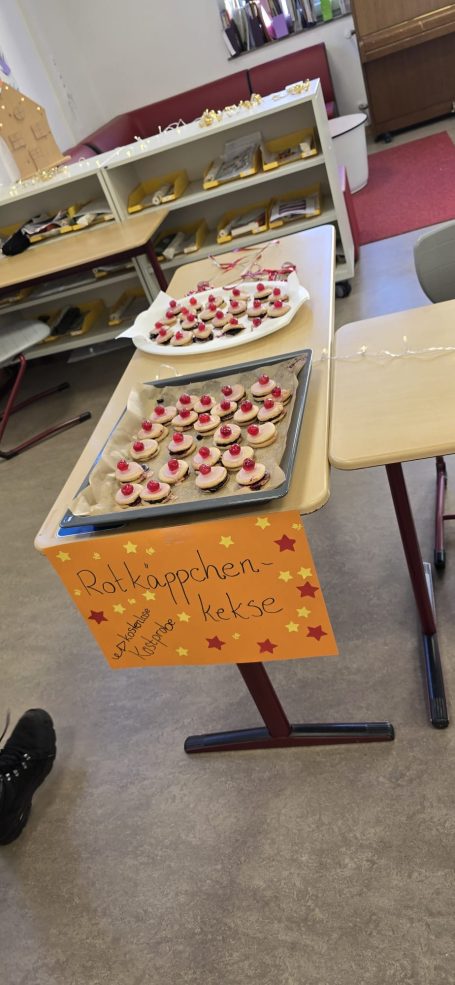 Auf einem Tisch stehen Platten mit kleinen, dekorierten Speisen und einer orangefarbenen Tafel.