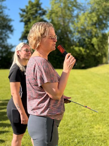 Frau mit Mikrophon steht auf einer Wiese