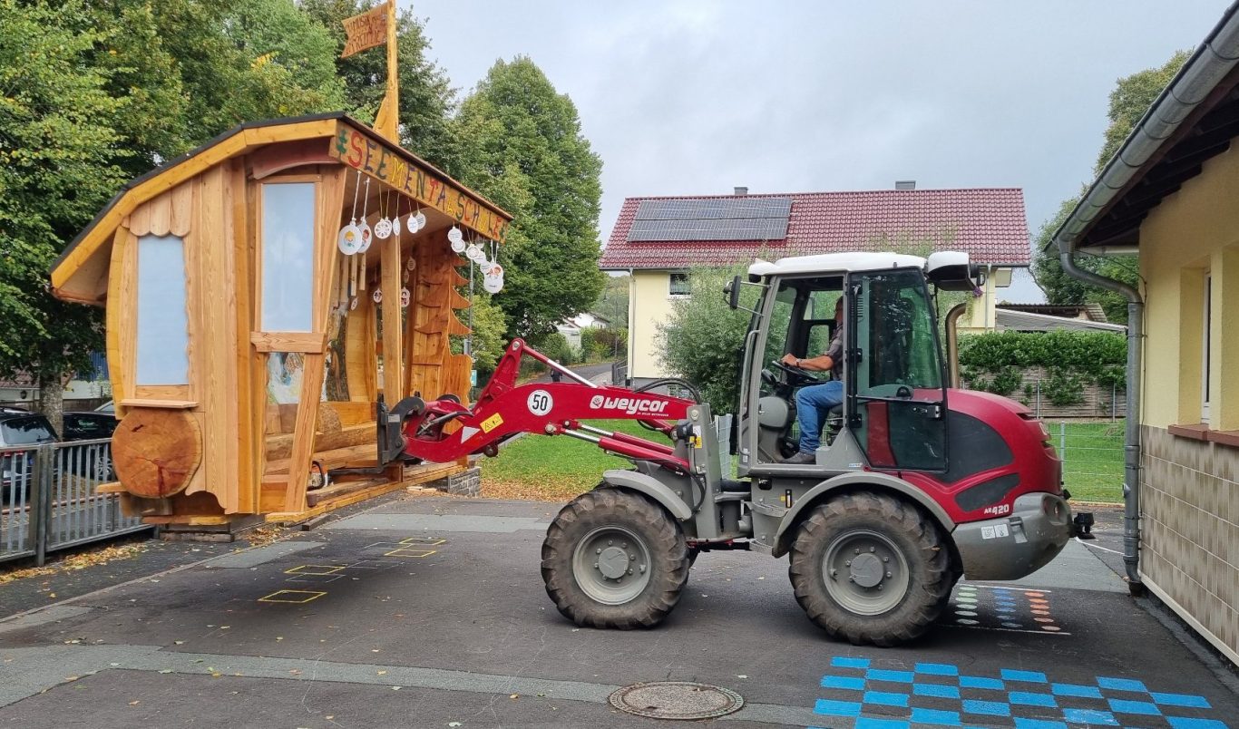 Ein Traktor hebt die Freundschaftsbank an.
